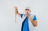 young-man-holding-chain-necklace-t-shirt-jacket-cap-looking-agitated-front-view_176474-57800
