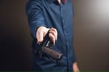 man-gives-gun-brown-surface_438099-2556