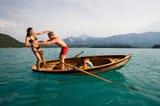 70066284-Young-man-pushes-girlfriend-from-a-rowing-boat-into-turquoise-water-Lake-Faak-Carinthia-Austria