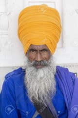 153404570-portrait-of-indian-sikh-man-in-orange-turban-with-bushy-beard-amritsar-india-close-up