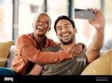 home-selfie-and-couple-on-a-couch-smile-and-loving-together-with-romance-profile-picture-and-marriage-social-media-black-woman-or-asian-man-on-a-2RARY5G