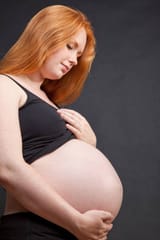 pregnant-woman-with-red-hair-holding-her-belly-3056793957