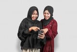 two-happy-muslim-women-in-hijab-laughing-while-using-smartphone-photo