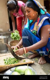 a-woman-in-a-traditional-blue-sari-dress-chops-okra-with-a-knife-held-by-her-feet-at-her-familys-home-in-rural-bihar-india-south-asia-2CC5P95