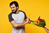 adult-man-refuses-eat-vegetables-with-hand_99043-1415