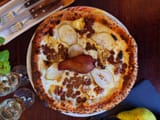 creme fraiche z mozzarellą Fior di Latte, gorgonzolą, plastrami świeżej gruszki i orzechami włoskimi, posypana deserową czekoladą B. Callebaut i płatkami migdałów, zwieńczona złotą gruszką