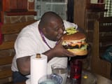 big fat black guy eating giant burger