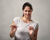 young-woman-disgusted-squeamishness-over-gray-wall-background-girl-disgusted-face-expression-100971942
