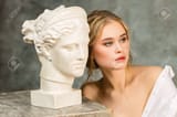 141192617-young-woman-posing-near-ancient-greek-statue