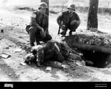 two-american-infantrymen-observing-a-dead-nazi-sprawled-on-the-rim-of-his-machine-gun-emplacement-smashed-during-the-d-day-assault-by-the-allies-in-southern-france-august-1944-2YXM7FW
