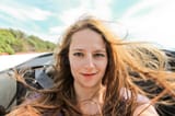 young-woman-taking-selfie-convertible-car-hair-turbulence-43772598