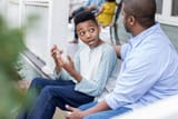 confused-preteen-son-talks-to-father-on-front-porch