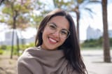 feliz-bonita-mujer-joven-posando-camara-parque-ciudad_1262-19158