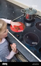 a-young-girl-holding-her-hand-over-a-hot-electric-stove-burner-BBACHK