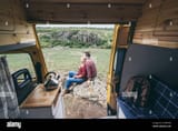 young-eastern-european-couple-travelling-by-yellow-camper-van-though-the-countryside-self-built-off-grid-motorhome-camping-in-the-wild-nature-2CAPPKM