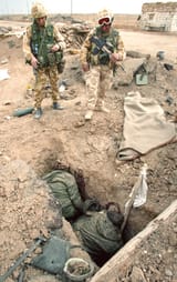 Two British soldiers contemplate the fate of two Iraqi counterparts, killed by artillery, one still clutching a white flag they had tried to raise, 1991