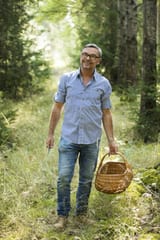 smiling-man-holding-basket-while-standing-in-forest-MAEF13020