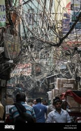 fussganger-wandern-in-engen-strasse-mit-grossens-tangled-birds-nest-von-stromkabeln-overhead-in-old-delhi-neu-delhi-delhi-indien-pk418r
