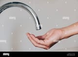 closeup-of-a-caucasian-man-indoors-with-his-hand-under-a-tap-waiting-for-water-to-come-out-TCFCDC