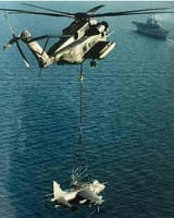 Harrier being carried to carrier by a helicopter