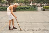 9256528-chinese-calligraphy-old-man-is-writing-han-characters-on-the-ground-with-brush-and-water-july-22