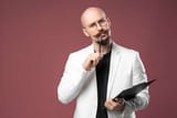 186354913-balded-man-with-mustache-and-beard-in-a-business-suit-holding-clipboard-and-pen-isolated-background