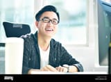 portrait-of-successful-asian-business-man-working-in-office-looking-at-camera-smiling-T1RXJ5