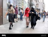 london-england-uk-two-young-muslim-women-walking-and-looking-at-an-F1MD5W