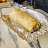 freshly-made-burrito-wrapped-in-foil-on-marble-table