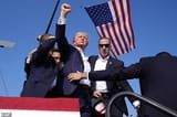 87307663-13633165-Trump_raises_his_fist_below_the_American_flag_with_blood_across_-a-11_1720967507471-547509777