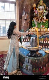 a-beautiful-hindu-devotee-pours-milk-over-a-lingam-near-a-statue-of-shiva-at-a-temple-in-richmondhill-queens-new-york-city-REEDYT