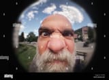 an-angry-man-looking-to-a-peephole-door-T6H70J