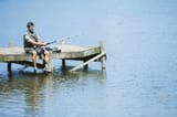 man-fishing-from-dock-over-lake-CAIF28570