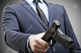 140333804-white-man-in-suit-holding-handgun-in-hand-and-trying-to-pass-it-to-someone