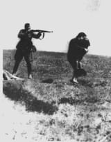 Ivangorod, Ukraine, A German policeman aims his rifle at a woman and her child, 1942