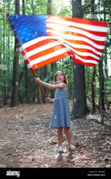 little-girl-carrying-an-american-flag-through-the-woods-C8606W
