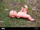 abandoned-and-broken-baby-doll-with-one-hand-missing-laying-n-the-BE0T5B-4059022596