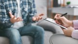 therapist-taking-notes-listening-to-patient-counseling-session-seated-across-their-clipboard-pen-323436445-4287138284