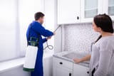 woman-and-worker-spraying-pesticide-in-kitchen
