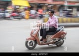 an-indian-man-riding-his-scooter-in-downtown-varanasi-on-a-late-afternoon-w7ktmy