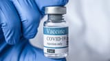 close-up-of-COVID-19-vaccine-vial-being-held-by-a-person-wearing-a-blue-PPE-glove-shutterstock_1678629760_Fotor-16x9-1