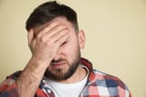 202350413-man-suffering-from-migraine-on-light-green-background-closeup