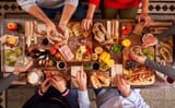 top-view-crop-anonymous-people-eating-tasty-food-while-sitting-wooden-table-with-assorted-appetizers-light-kitchen_935394-2765