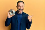 middle-age-hispanic-man-holding-compact-disc-pointing-thumb-up-to-side-smiling-happy-open-mouth-middle-age-hispanic-man-227181484-981179293