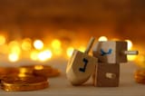 religion-concept-jewish-holiday-hanukkah-wooden-dreidels-spinning-top-chocolate-coins-over-wooden-table-bokeh-163841815