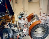 ap15-KSC-71PC-345HR - Dave Scott (right) examines the flight Rover during stowage against the LM descent stage