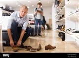 man-trying-on-suede-and-leather-loafers-in-store-2H8RPNE