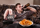 man-sitting-on-the-couch-holding-a-remote-and-a-beer-bottle