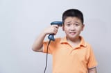 EastAsianKid-BarodeScanner-PointedToHead-Dismay