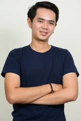 portrait-happy-young-asian-man-smiling-with-arms-crossed_251136-46896
